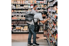Image A man bending down to read a food label on the shelf in a grocery store.